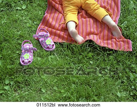 detail of little child lying on towel in grass, with little shoes beside View Large Photo Image Stock Image - detail of little child lying on towel in grass, with little shoes beside. Fotosearch