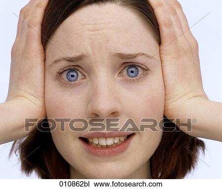 Stock Image - Distressed looking young woman covering her ears with the hands. Fotosearch