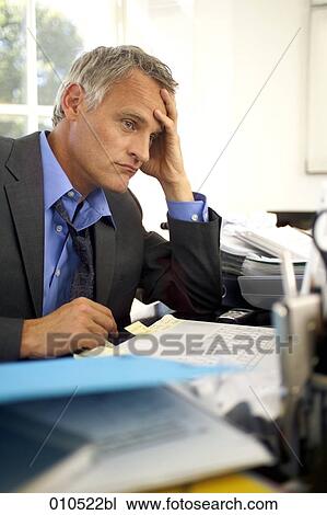 exhausted looking mature businessman sitting at desk View Large Photo Image Stock Image - exhausted looking mature businessman sitting at desk. Fotosearch