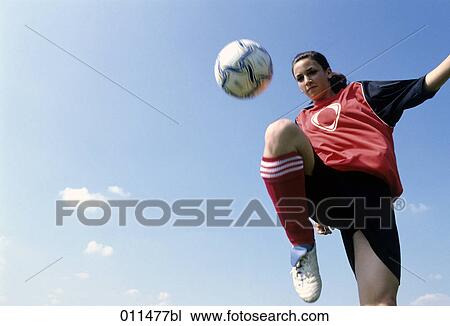 Stock Image - female teenage footballer bouncing the ball on her knee. Fotosearch