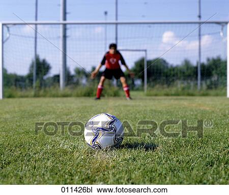 Stock Image - football lying on penalty spot with goalkeeper in background . Fotosearch