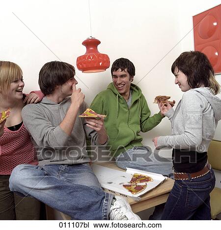 Stock Image - Four friends sitting together eating pizza. Fotosearch