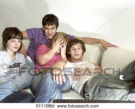 Stock Image - Four friends watching tv, one girl looking frightened. Fotosearch
