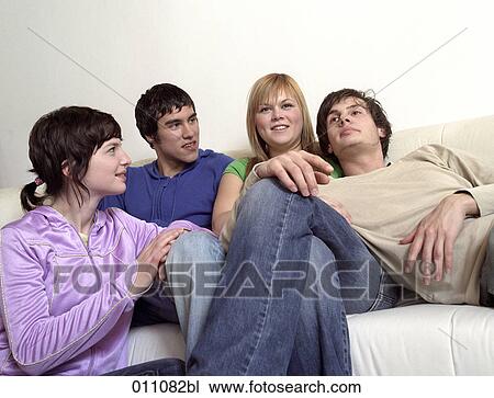 Stock Image - Four teenagers together on a sofa. Fotosearch