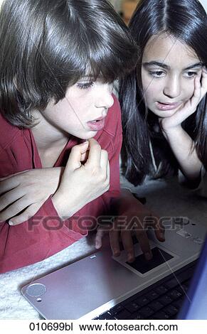 Stock Image - girl showing boy how to work with a notebook computer (close-up). Fotosearch