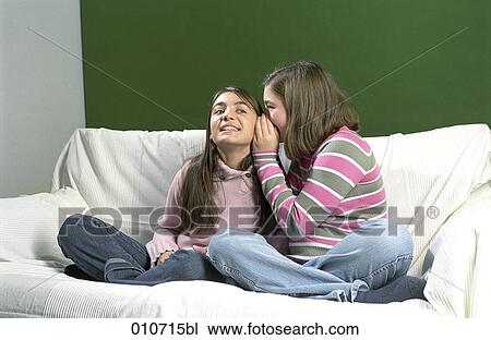 girl sitting on sofa whispering in another girl´s ear View Large Photo Image Stock Image - girl sitting on sofa whispering in another girl´s ear. Fotosearch