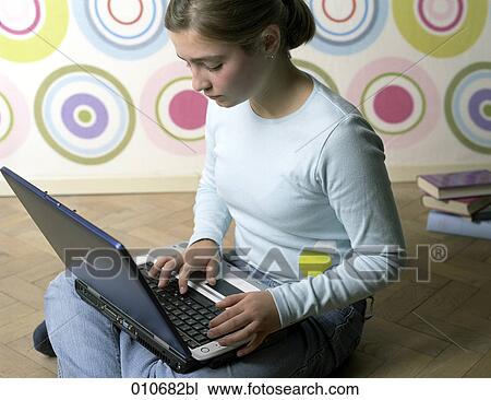 Stock Image - girl sitting on the floor, working with notebook computer. Fotosearch
