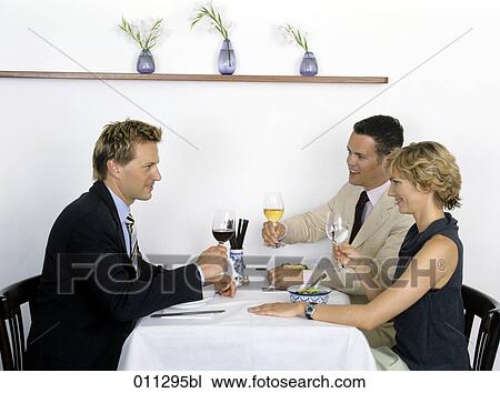 Stock Image - group of businessmen raising their glasses at lunch. Fotosearch