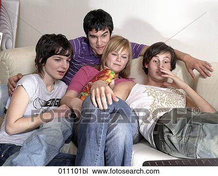 Stock Image - Group of four friends watching tv together. Fotosearch