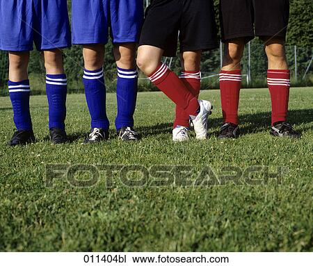 Stock Image - legs of football players standing on grass. Fotosearch