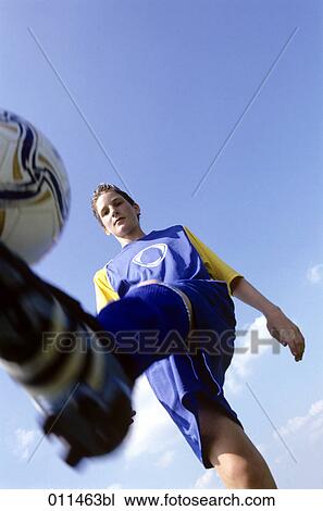 Stock Image - low angle view of football player bouncing the ball. Fotosearch