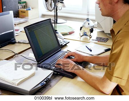 male office worker at office desk typing with laptop PC View Large Photo Image Stock Image - male office worker at office desk typing with laptop PC. Fotosearch