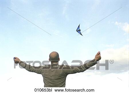 Stock Image - man flying a blue kite. Fotosearch