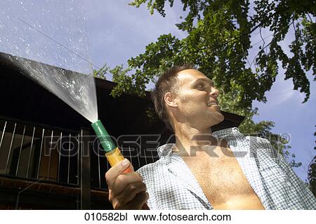 man looking while holding a garden hose View Large Photo Image Stock Image - man looking while holding a garden hose. Fotosearch
