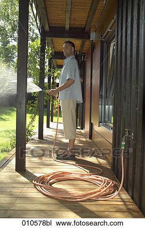 man standing on veranda watering the lawn View Large Photo Image Stock Image - man standing on veranda watering the lawn. Fotosearch