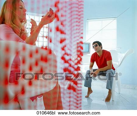 Stock Image - man watching his girlfriend applying make-up. Fotosearch