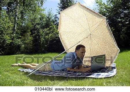 man with his laptop computer under a sunshade View Large Photo Image Stock Image - man with his laptop computer under a sunshade. Fotosearch