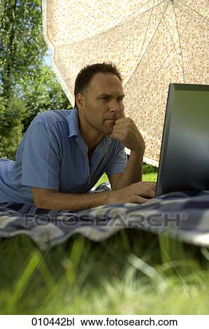 man with his laptop computer under a sunshade View Large Photo Image Stock Image - man with his laptop computer under a sunshade. Fotosearch
