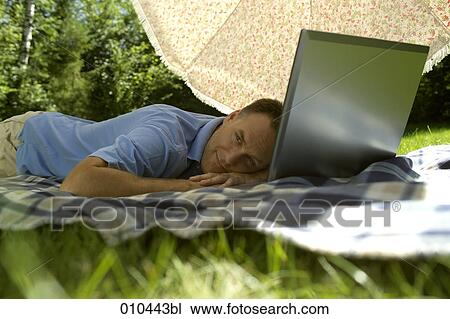 man with his laptop computer under a sunshade, day-dreaming View Large Photo Image Stock Image - man with his laptop computer under a sunshade, day-dreaming. Fotosearch