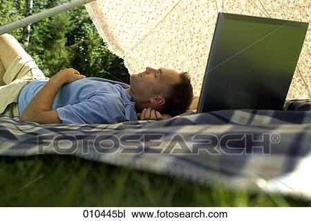 man with his laptop computer under a sunshade, dozing View Large Photo Image Stock Image - man with his laptop computer under a sunshade, dozing. Fotosearch