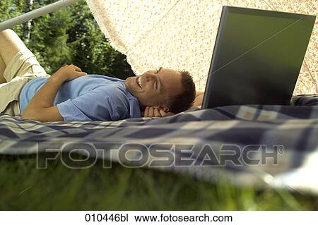 man with his laptop computer under a sunshade, being happy View Large Photo Image Stock Image - man with his laptop computer under a sunshade, being happy. Fotosearch