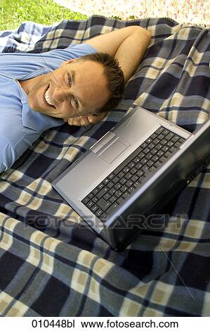 Stock Image - man working with laptop in his garden. Fotosearch