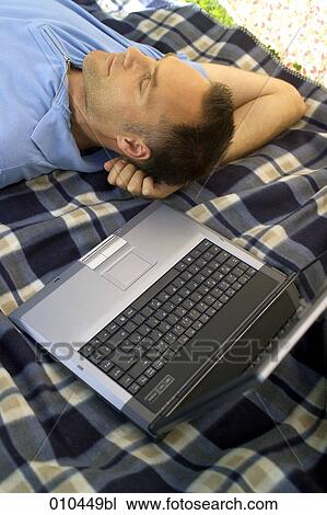 Stock Image - man working with laptop in his garden. Fotosearch