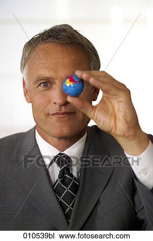 mature businessman holding a miniature globe before his face View Large Photo Image Stock Image - mature businessman holding a miniature globe before his face. Fotosearch