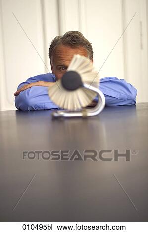 Stock Image - mature businessman looking at rolodex. Fotosearch