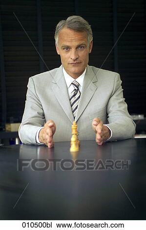 mature businessman sitting at desk and making explanations with chess pieces View Large Photo Image Stock Image - mature businessman sitting at desk and making explanations with chess pieces. Fotosearch