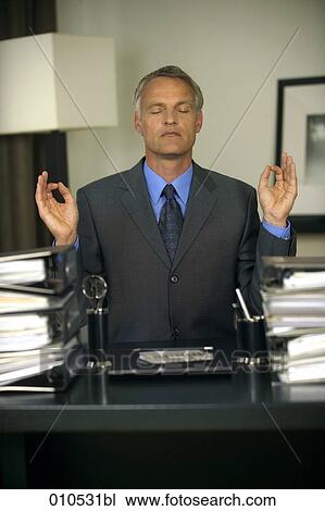 Stock Image - mature businessman sitting at his desk and meditating. Fotosearch