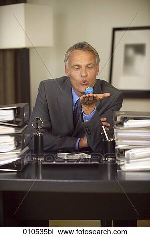 mature businessman sitting at his desk and holding a little globe in his hand View Large Photo Image Stock Image - mature businessman sitting at his desk and holding a little globe in his hand. Fotosearch