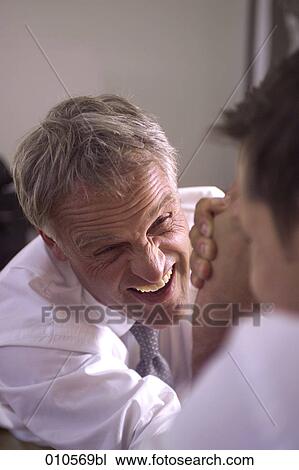 Stock Image - mature man arm wrestling with younger opponent. Fotosearch