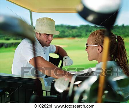 Stock Image - models posing in electric caddy on golf course. Fotosearch