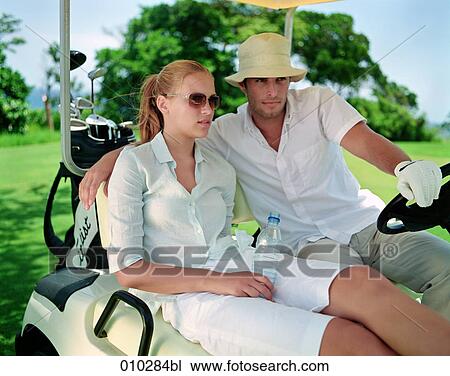 Stock Image - models posing in electric caddy on golf course. Fotosearch