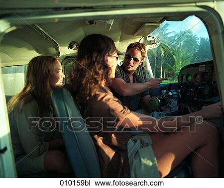 Stock Image - pilot in small propeller plane talking to female passengers. Fotosearch