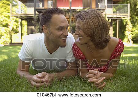 Stock Image - portrait of couple lying in the grass. Fotosearch