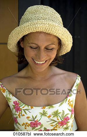 Stock Image - portrait of happy woman in flowery dress wearing a straw hat. Fotosearch