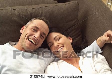 Portrait of laughing couple on sofa View Large Photo Image Stock Image - Portrait of laughing couple on sofa. Fotosearch