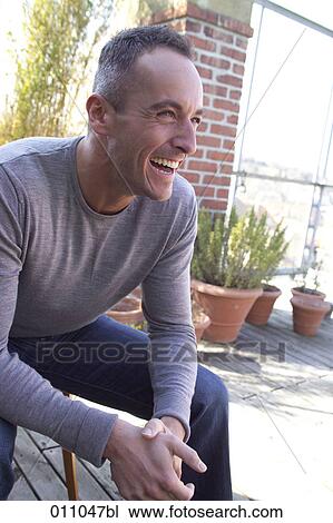 Portrait of laughing young man sitting on a terrace View Large Photo Image Stock Image - Portrait of laughing young man sitting on a terrace. Fotosearch