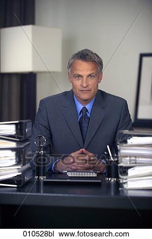 Stock Image - portrait of mature businessman sitting at his desk. Fotosearch