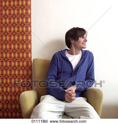 Stock Image - Portrait of teenage boy sitting in arm chair. Fotosearch