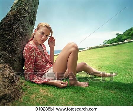 Stock Image - portrait of teenager (16-19 years) leaning on palm tree. Fotosearch
