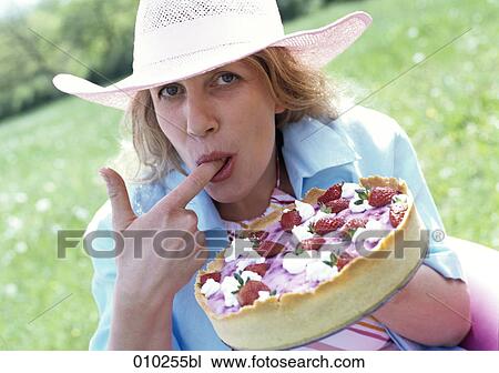 Stock Image - portrait of woman (35-40 years) nibbling at cake. Fotosearch