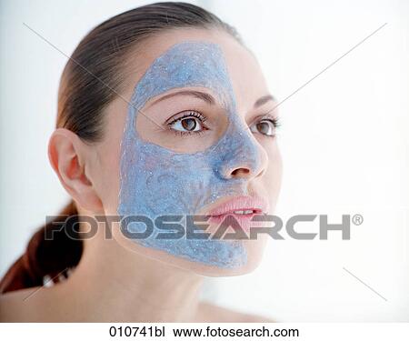 Stock Image - portrait of you woman with one face side covered by mud mask. Fotosearch