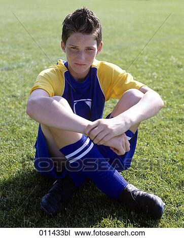 Stock Image - portrait of young football player sitting on grass. Fotosearch