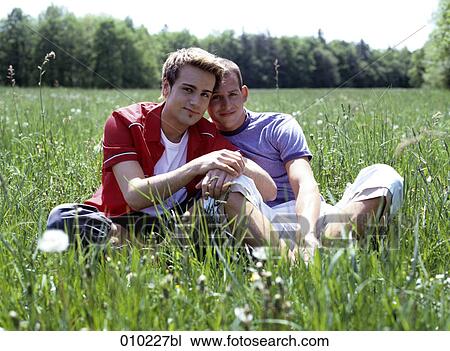 Stock Image - portrait of young gay couple (20-25 years) sitting in the grass. Fotosearch