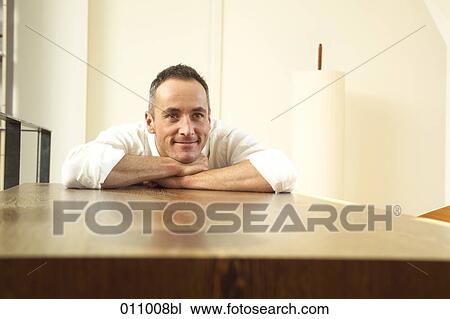 Portrait of young man resting his arms on a table View Large Photo Image Stock Image - Portrait of young man resting his arms on a table. Fotosearch