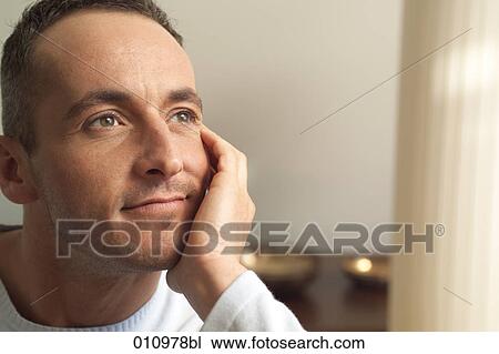 Stock Image - Portrait of young man resting his head in one hand. Fotosearch