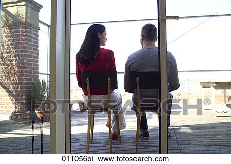 Rear view of young couple sitting on a terrace and having a conversation View Large Photo Image Stock Image - Rear view of young couple sitting on a terrace and having a conversation. Fotosearch